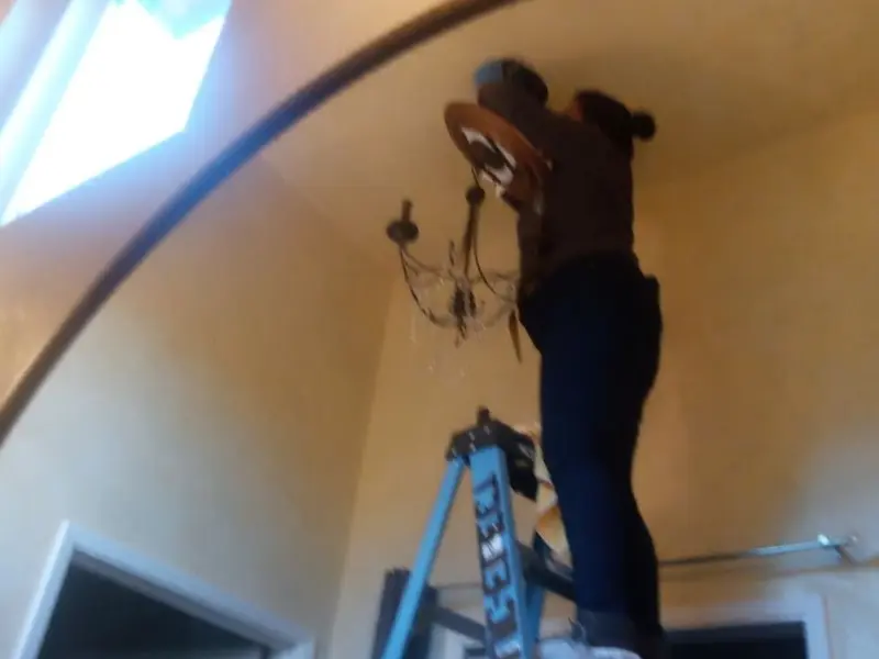 Electrician installing a chandelier in a Marine City residence